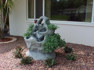 Charcoal colored 360 degree fountain, 36" scale that is raised up on a custom base for additional heighth