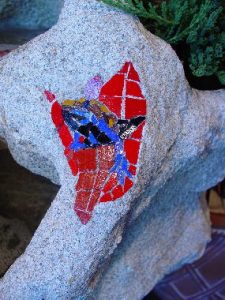 Close up of Mosaic frog climbing from red flower